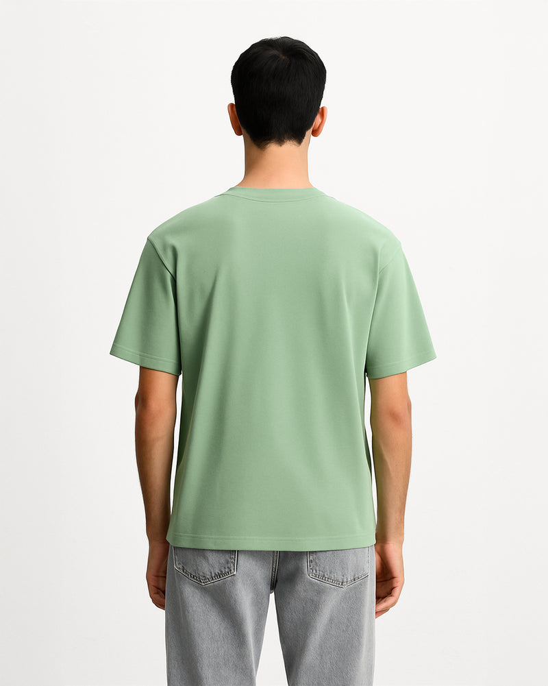 Person wearing a light green t-shirt and gray jeans on a white background.