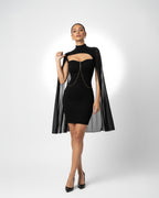 Woman wearing a black dress with a cape on a white background