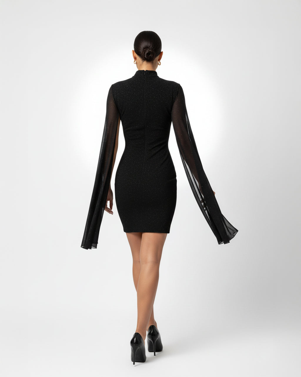 Black dress with sheer sleeves worn by a model on a white background