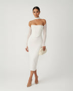 Woman wearing a white strapless dress with sheer sleeves against a white background