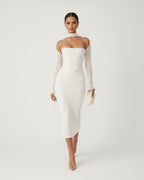 Woman wearing a white strapless dress with long sleeves on a plain background