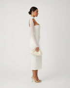 Woman wearing a white dress with sheer sleeves against a plain background