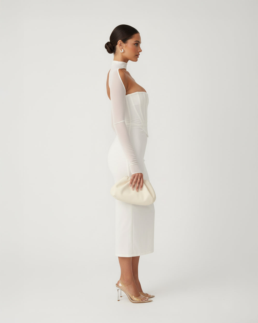 Woman wearing a white dress with sheer sleeves against a plain background