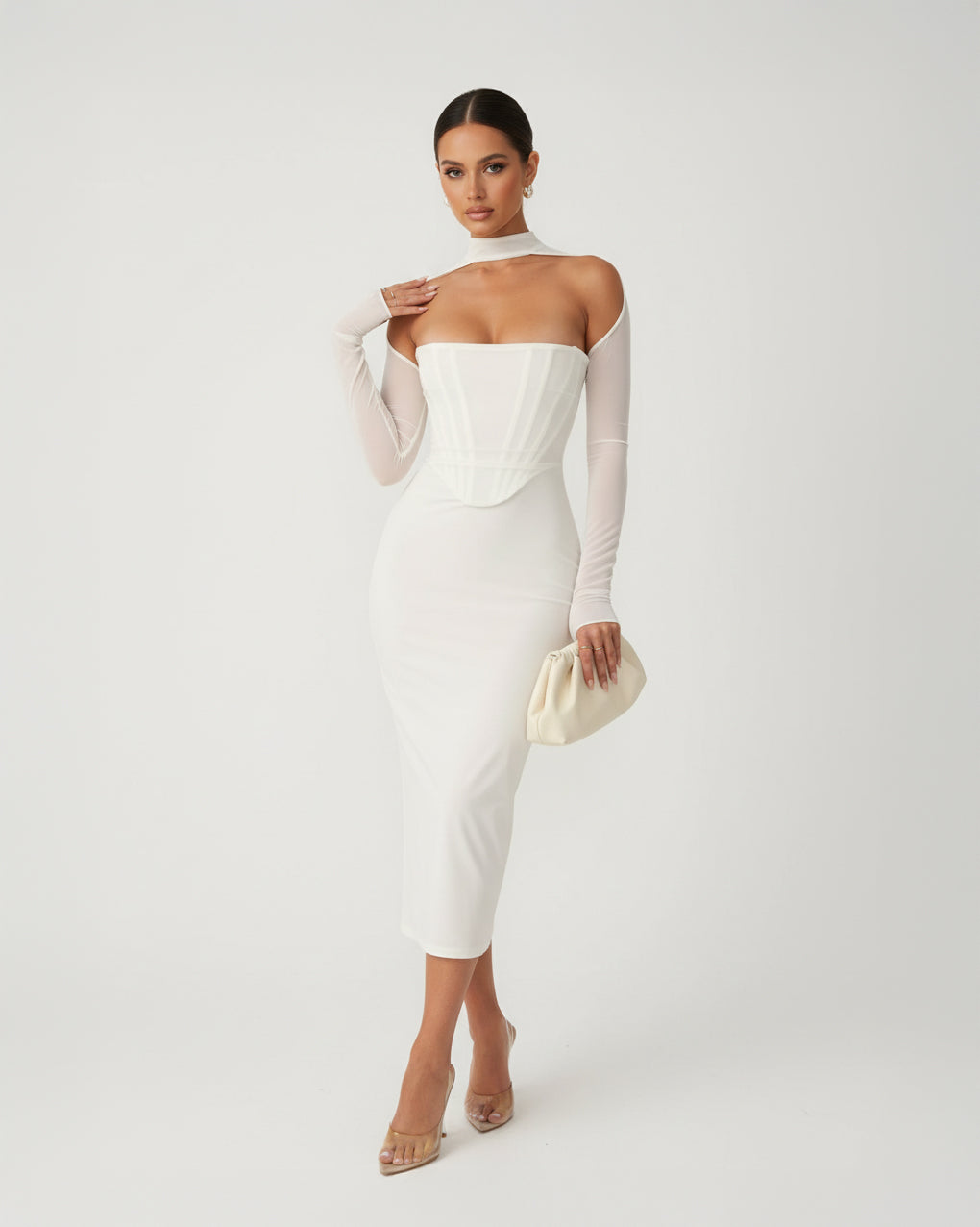 Woman wearing a white off-shoulder dress with sheer sleeves on a plain background
