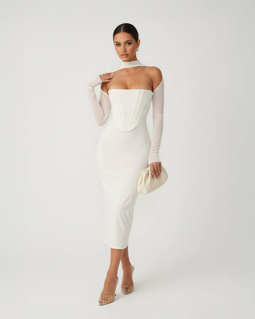 Woman wearing a white off-shoulder dress with sheer sleeves on a plain background